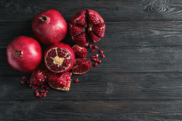 Ripe pomegranates and seeds on wooden background, flat lay with space for text