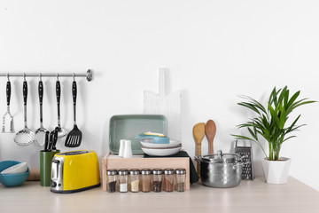 Set of clean cookware, dishes, utensils and appliance on table at white wall
