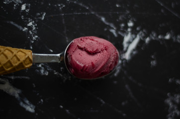 Homemade strawberry ice cream with one large scoop on black background