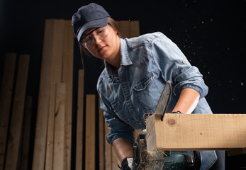 Young woman  using modern electric  saw in the workshop