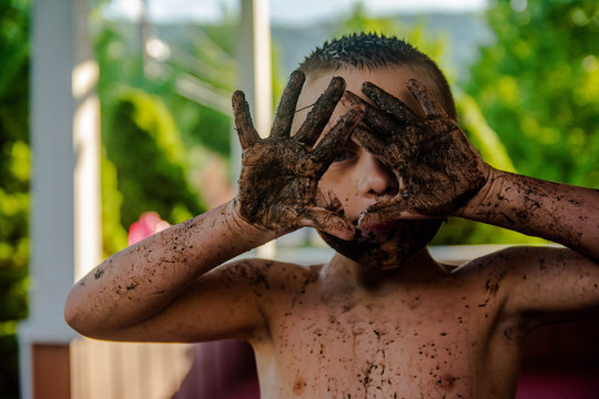 Boy with mud all over his hands