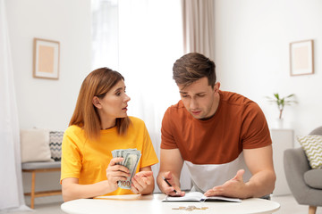 Sad couple counting money in living room