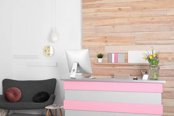 Stylish interior of beauty salon with modern reception desk near wooden wall