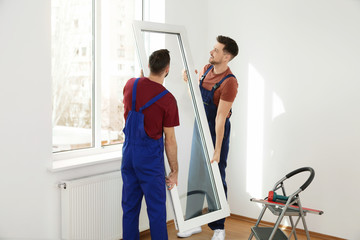 Construction workers installing plastic window in house