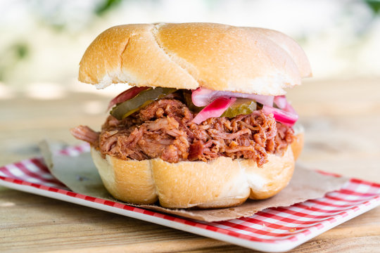Barbeque slow cooked pulled pork sandwich with pickles and red onions, covered in a sweet and spicy barbecue sauce.