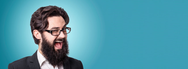 Funny handsome businessman looking at camera and winking, panoramic image over blue background