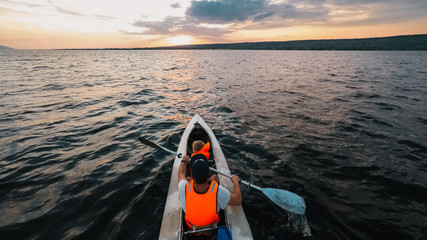 Father and a son go kayaking in the sunset