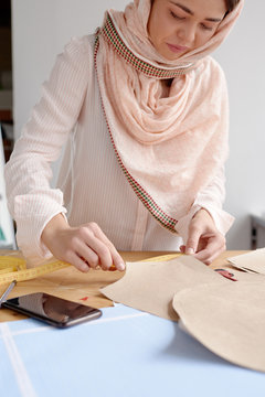 Woman measuring paper pattern for sewing