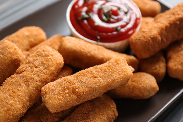 Plate of tasty crispy cheese sticks with sauce, closeup