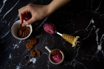Strawberry ice cream and woman hand holding chocolate cookies