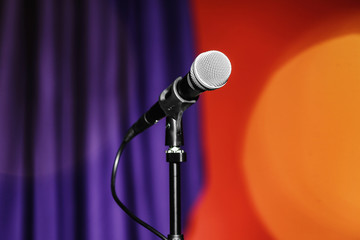 Stand with microphone on color background. Blurred lights