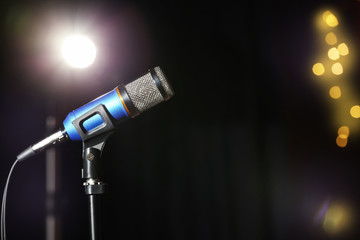 Stand with microphone on stage, space for text. Blurred lights