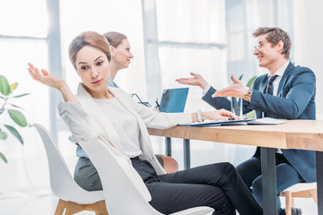Fototapeta premium attractive emotional recruiter gesturing near man in glasses talking during job interview