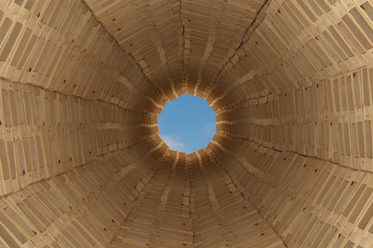 Blick in kreisförmigen Tunnel aus Europaletten Holzpaletten - Blick nach oben - blauer Himmel