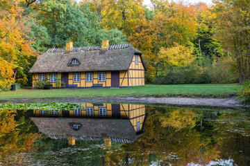 Fototapeta na wymiar Old yellow half timbered house with thatched roof in Charlottenlund forest, Denmark