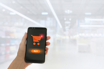 Hand holding mobile smart phone with my shopping carts screen on Supermarket blur background.