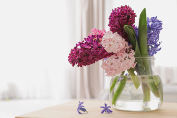 Beautiful hyacinths in glass vase on table indoors, space for text. Spring flowers