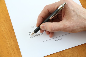 agreement and hand with pen about to sign it on wooden table