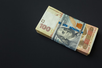 Value of Ukrainian hryvnia and American dollars. A pack of Ukrainian hryvnia wrapped one hundred dollar bill