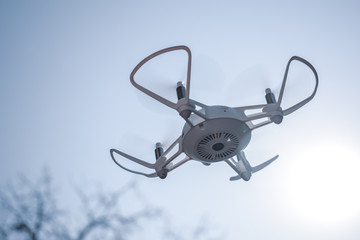 Quadcopter drone hovering in a blue sky