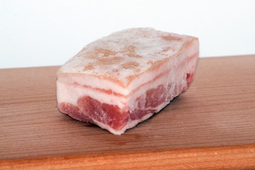 large piece of frozen pork belly on a cutting board