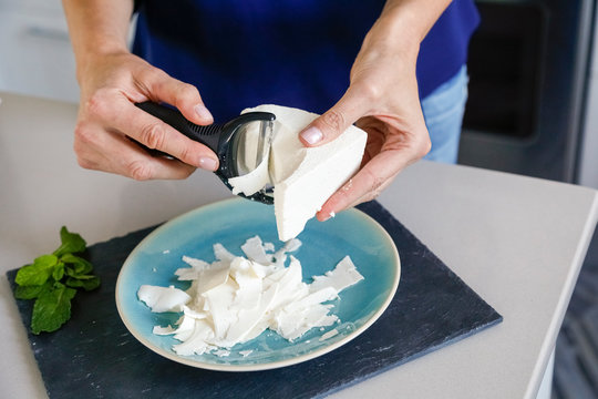 Hands of woman shaving ricotta