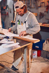 Male carpenter working on old wood in a retro vintage workshop.