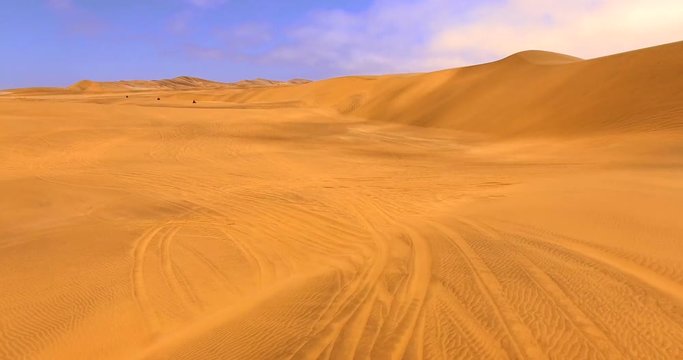 NAMIB-NAUKLUFT NATIONAL PARK, NAMIBIA. Aerial 4K view of four tourists riding ATVs along windy and sandy desert terrain.