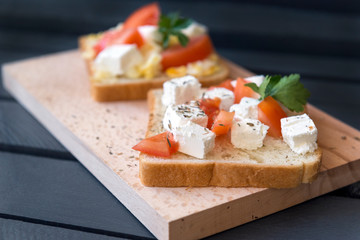 sandwich with feta and tomato and greens on cutting Board