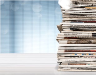 Pile of printed newspapers on blue background