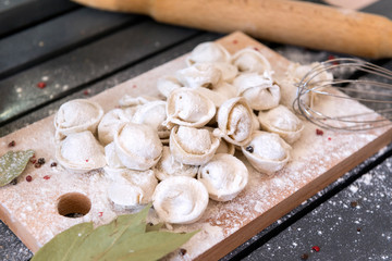 a lot of raw dumplings with flour on the cutting Board, rolling pin, whisk, Bay leaf, spices, semifinished products
