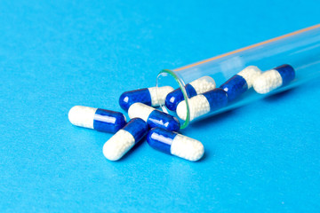 Medicine blue capsules (pills) in the test tube on blue background. Copy space. Medical background, template.