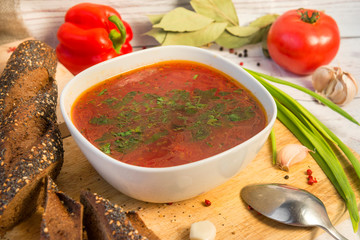 bowl of soup, soup with herbs, bread, onion ,tomato, pepper, spoon