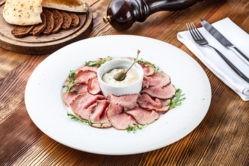 Close up view on traditional italian cuisine Vitello tonnato. A dish with pickled veal tuna cream sauce and bread on wooden background. Copy space for design, text. Snack before lunch. Close up food - obrazy, fototapety, plakaty