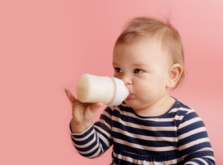 Portrait of a cute toddler drinking milk from the bottle, one year old food concept