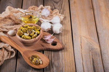 Grilled olives with garlic, olive oil and spices on rustic wooden table