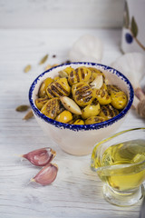 Grilled olives with garlic, olive oil and spices on white rustic table