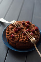 Dessert for two. Delicious chocolate cake with chocolate icing and raw cherries served with two vintage forks on dark background