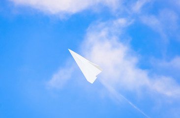 White paper airplane in a blue sky with clouds. The message symbol in the messenger