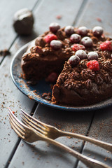 Delicious homemade chocolate cake with chocolate icing and raw berries with vintage forks on dark background