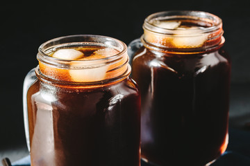 Coffee with ice in a glass mason jars on the napkin at dark background