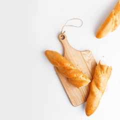 Bread on wooden cutting board isolated on white background, top view
