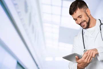 Naklejka na ściany i meble Male doctor with stethoscope on blurred hospital background