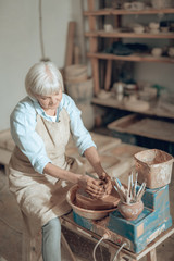 Cropped photo of elderly craftswoman making earthenware in potter's studio