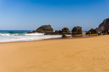 View of Adraga sandy beach with stones near Sintra