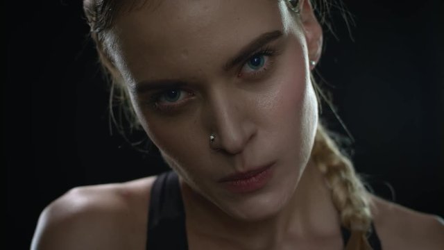 Aggressive woman biting lips looking to camera on black background