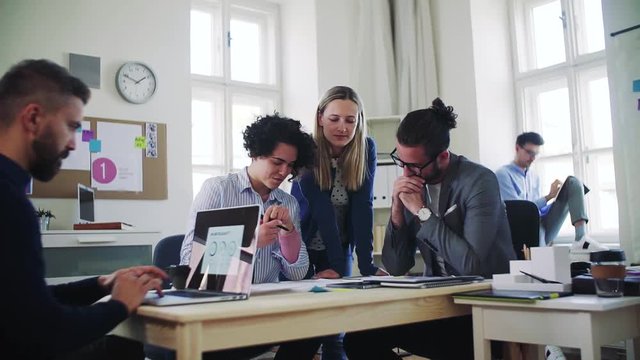 Group of young businesspeople with laptop working together in a modern office.
