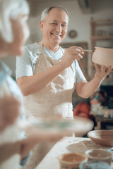 Low angle of happy mature craftsman working in potter's studio