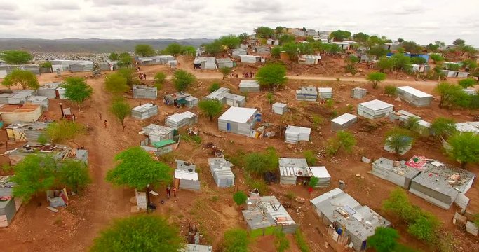 Fragile houses within harsh weather conditions and deserted terrain. Aerial 4K view of typical architecture in sub-Saharan Africa.