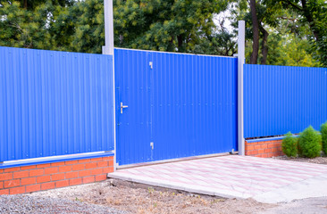 Fence and gate from sheets of blue corrugated metal.